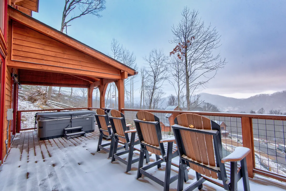 A mountain-view deck with Adirondack chairs and a hot tub, offering panoramic views of the surrounding landscape. The scene evokes a sense of calm, perfect for stargazing or soaking while taking in the sunset.